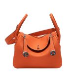 A taupe pebbled vegan leather Lindy bag with side-set handles, a shoulder strap, and silver circular turn-locks. Additional product view 4.