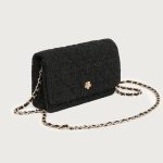 A small black diamond-quilted vegan leather flap bag with a gold flower emblem and a leather-woven gold chain strap. Additional product view 6.