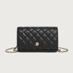A small black diamond-quilted vegan leather flap bag with a gold flower emblem and a leather-woven gold chain strap.
