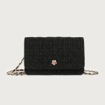 A small black diamond-quilted vegan leather flap bag with a gold flower emblem and a leather-woven gold chain strap. Additional product view 3.