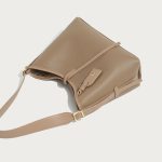 A taupe pebble-grain vegan leather hobo worn on the shoulder, showing gold hardware and a striped interior lining. Additional product view 7.