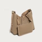 A taupe pebble-grain vegan leather hobo worn on the shoulder, showing gold hardware and a striped interior lining. Additional product view 8.