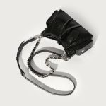 A glossy black crinkled vegan leather underarm bag with snap cargo side pockets, a chain strap, and a small luggage tag. Additional product view 5.