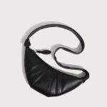 A coffee brown vegan leather croissant bag with vertical ribbed panels, knotted strap joins, and a curved top zipper. Additional product view 5.