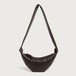A coffee brown vegan leather croissant bag with vertical ribbed panels, knotted strap joins, and a curved top zipper.