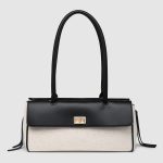 A rectangular straw raffia baguette with a black vegan leather flap, gold turn-lock, dual straps, and side leather tassels. Additional product view 3.