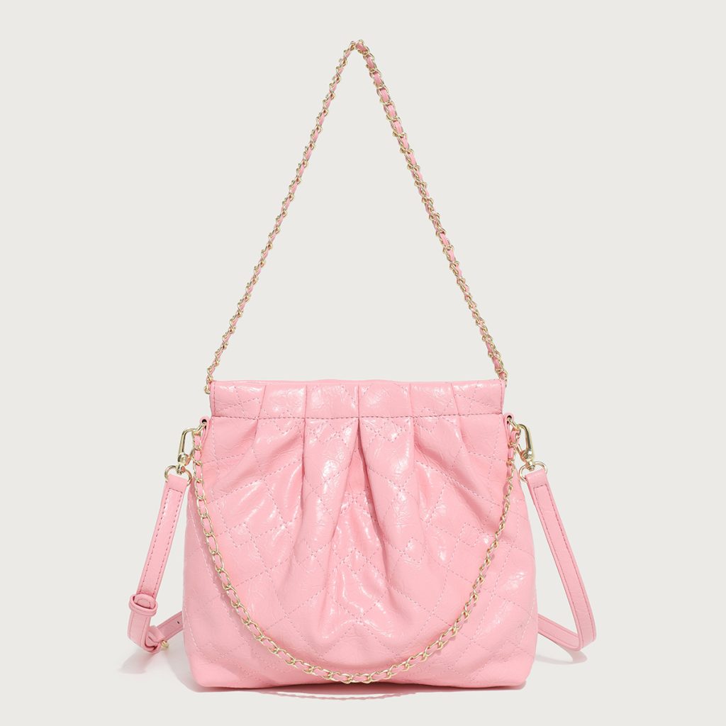A pastel pink quilted vegan leather pouch with a gathered top, gold chain strap, and a detachable flat crossbody strap.