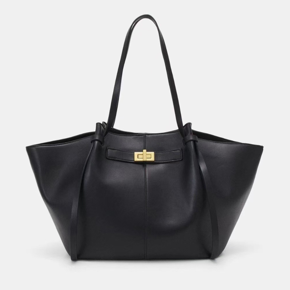 A large black vegan leather flared tote with long shoulder straps and a gold turn-lock on a slim horizontal strap.