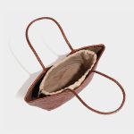 A black woven vegan leather shopper tote with braided handles and a cognac brown drawstring inner pouch. Additional product view 6.
