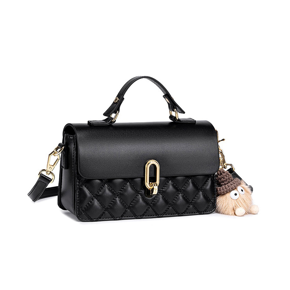 A black vegan leather flap handbag with a quilted lower panel, gold oval clasp, top handle, and a tan furry bag charm.