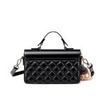 A black vegan leather flap handbag with a quilted lower panel, gold oval clasp, top handle, and a tan furry bag charm. Additional product view 3.
