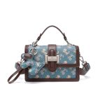 A beige and tan monogram satchel with a top handle, gold buckle, teddy-bear charm, and two detachable shoulder straps. Additional product view 3.