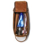 A vintage brown leather toiletry bag with dual zippers, a front flap pocket, side handle, and brass feet on a white background. Additional product view 5.